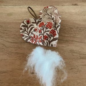 Genähtes Herz neben etwas Füllwatte auf einem Holztisch